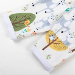 Manche de pyjama bébé décorée d’animaux de la forêt et d’arbres colorés sur fond blanc.