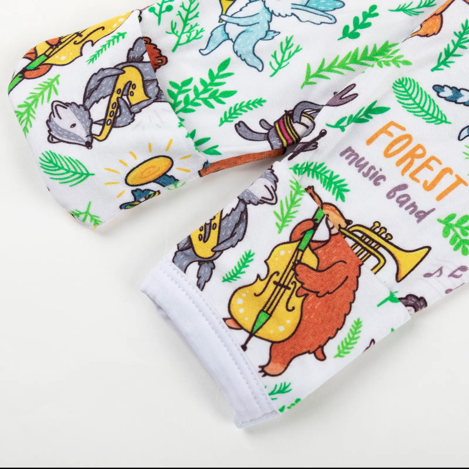 Manche de vêtement bébé décorée d’animaux de la forêt jouant de la musique, avec feuilles vertes et notes colorées.