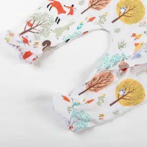 Bas de pyjama bébé décoré d’animaux de la forêt et d’arbres colorés sur fond blanc.