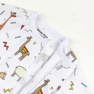 Haut de pyjama bébé décoré de lamas colorés et formes géométriques sur fond blanc.