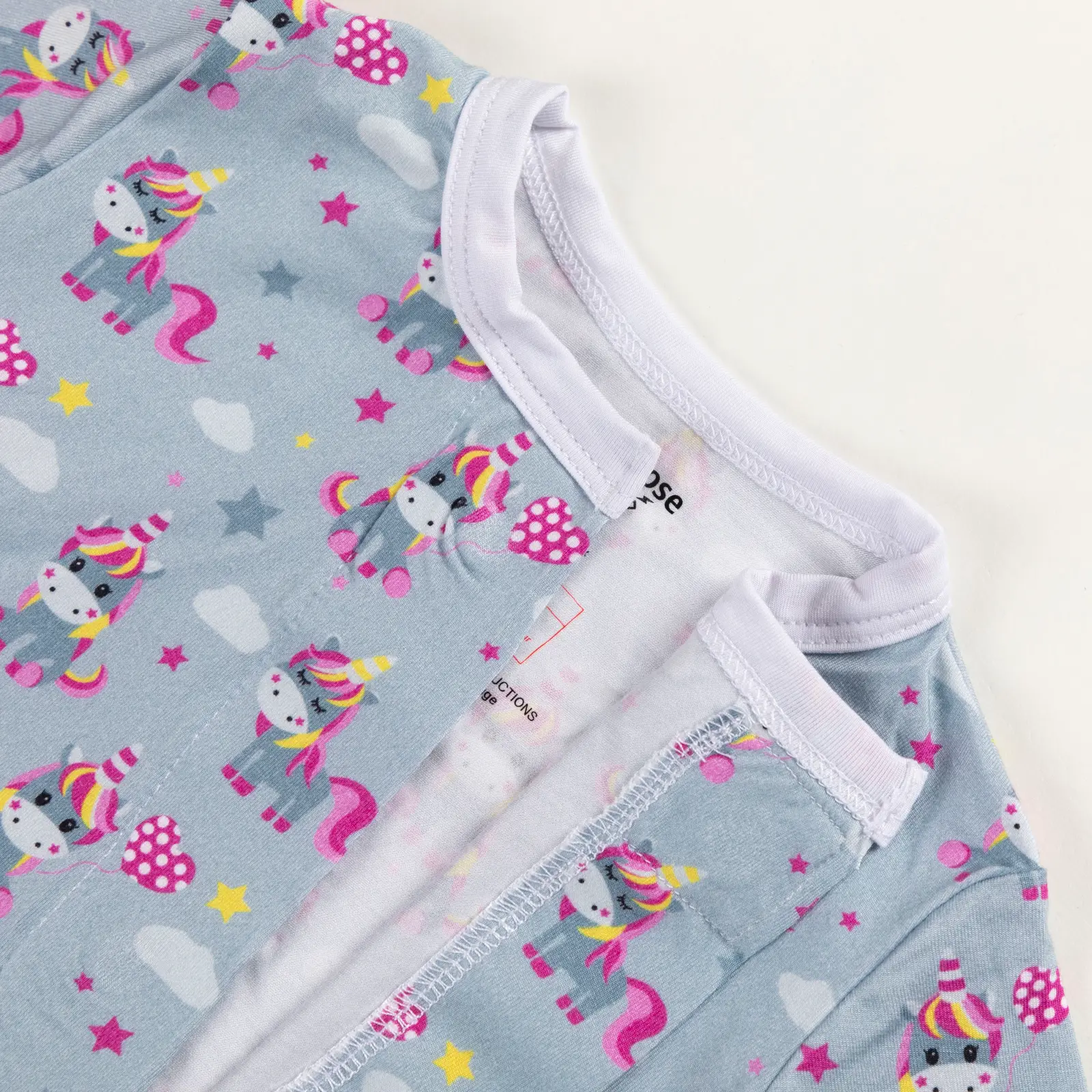 Haut de pyjama bébé bleu décoré de licornes colorées, étoiles et nuages.