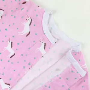 Haut de pyjama bébé rose décoré de licornes blanches et détails fantaisie.