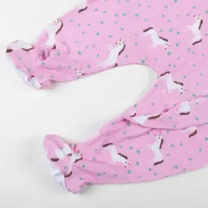 Bas de pyjama bébé rose décoré de licornes blanches et détails fantaisie.
