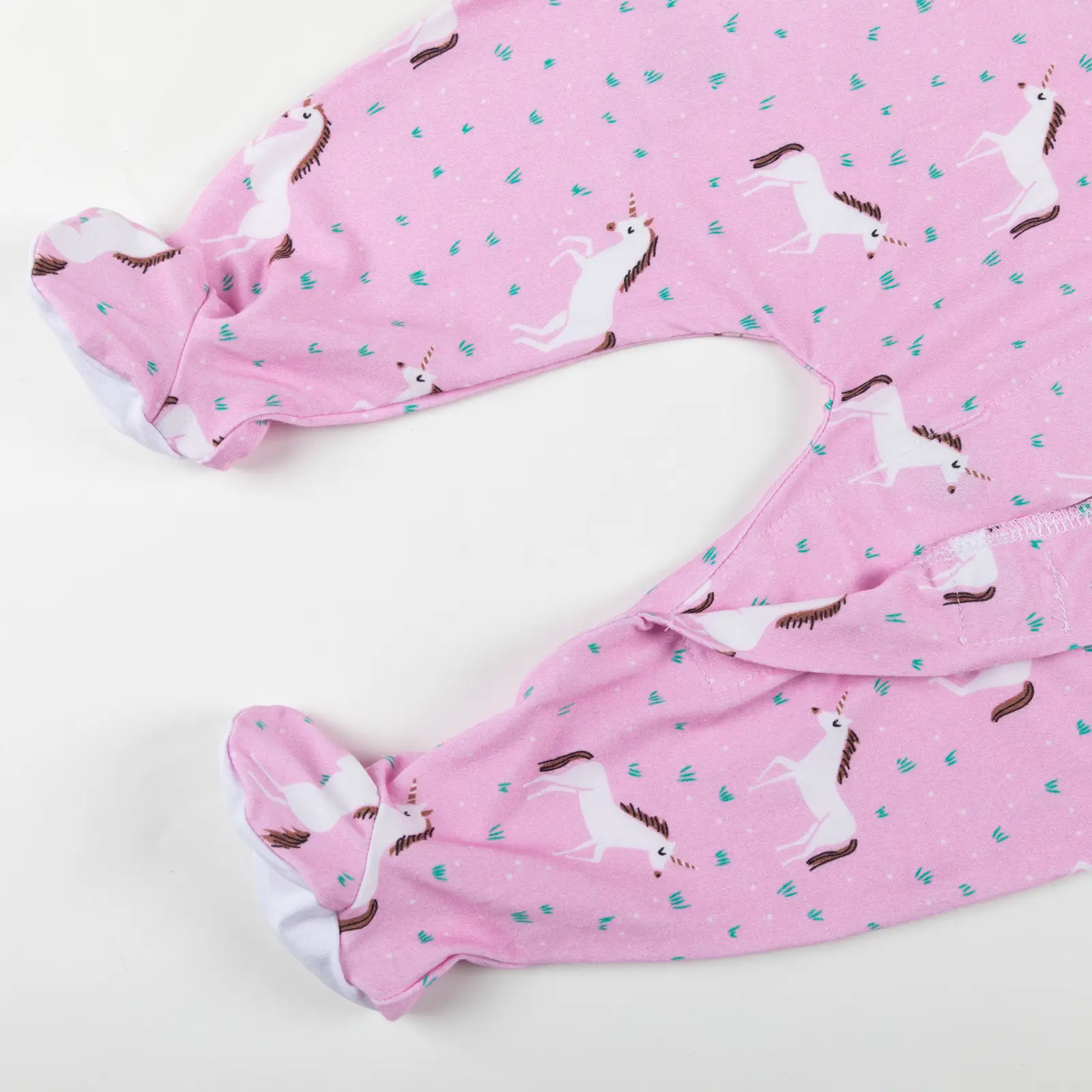 Bas de pyjama bébé rose décoré de licornes blanches et détails fantaisie.