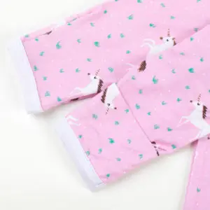 Gros plan sur les manches d'un pyjama rose pour bébé avec motifs licornes et détails de poignets réversibles.