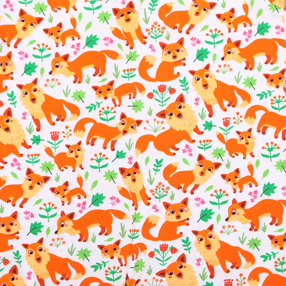 Motif enfantin représentant des renards orange dans différentes poses, entourés de feuilles vertes et de fleurs colorées sur fond blanc.
